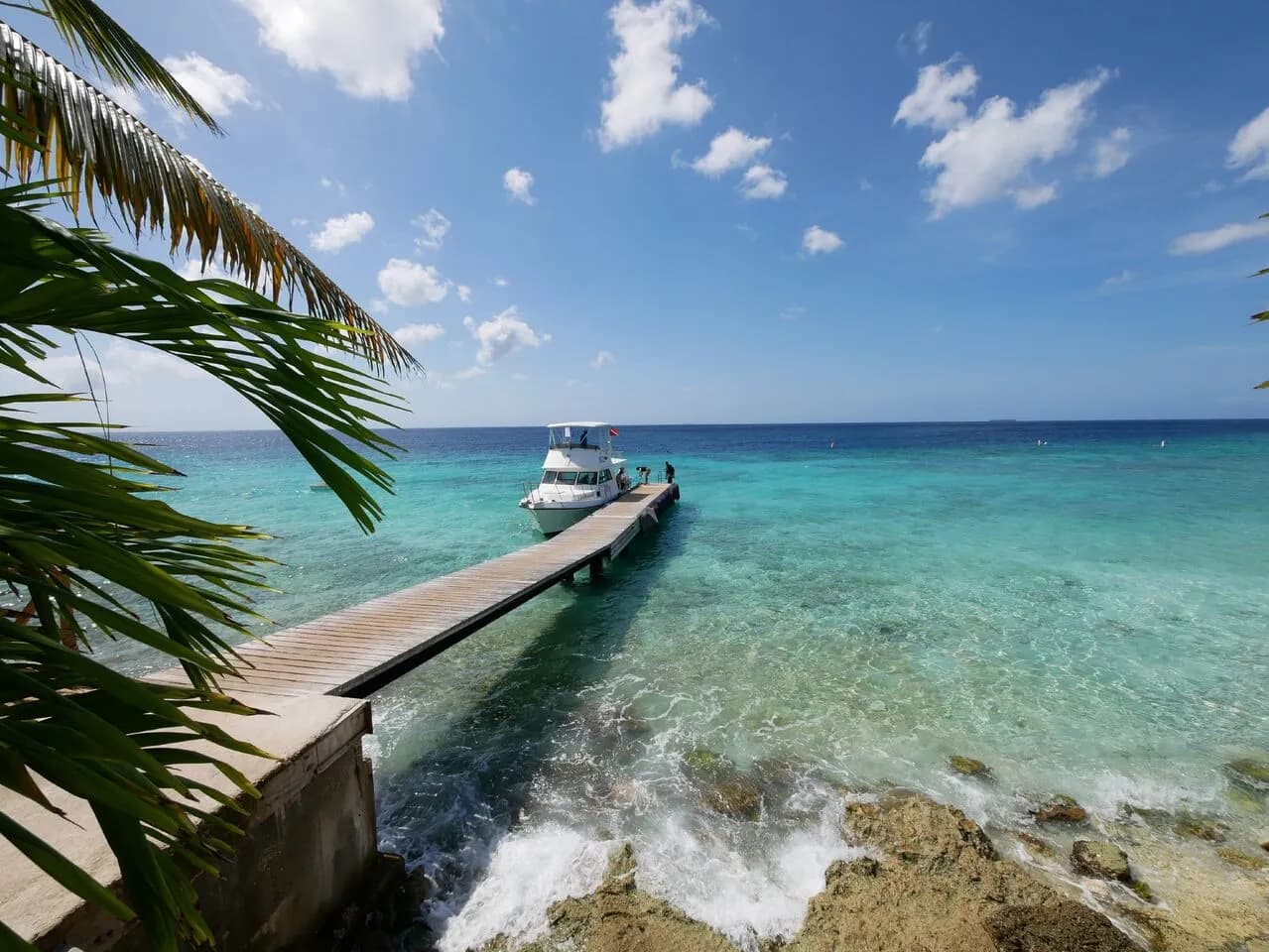 A boat docked on a pier in the ocean, surrounded by calm waters and a picturesque view of the horizon.